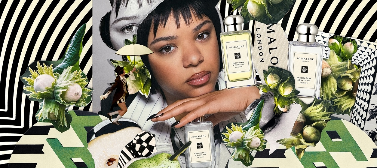 Person with Jo Malone London bottles, pears, and flowers on a black-and-white striped background.